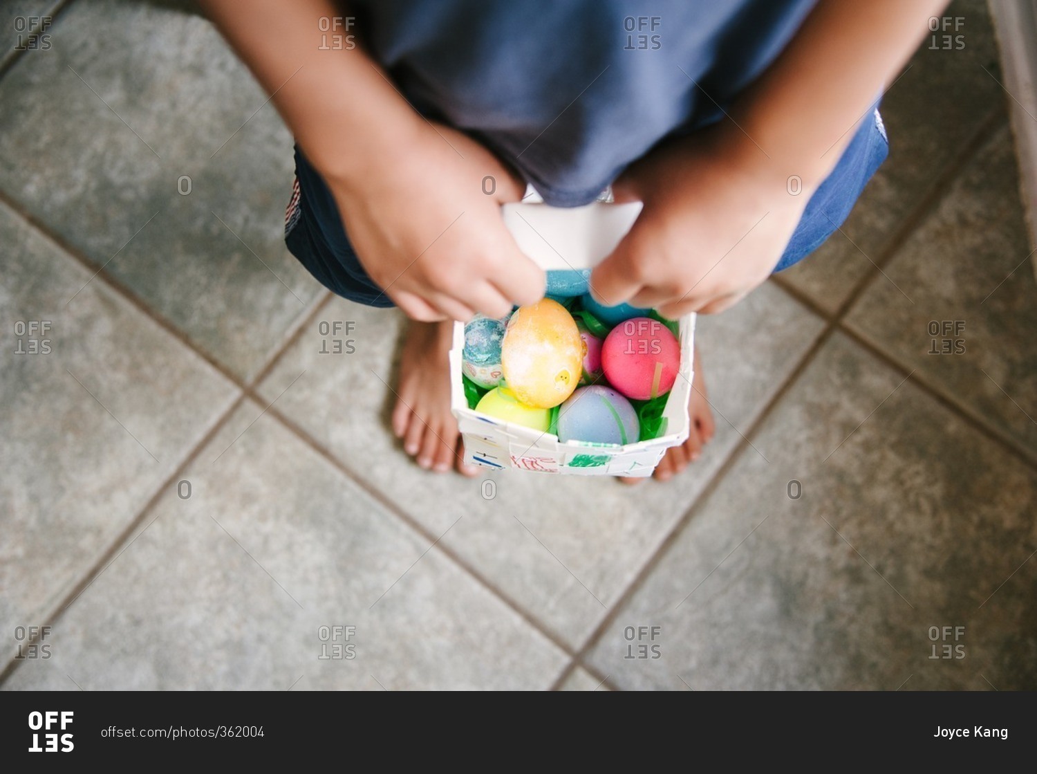Overhead view of a child holding a basket of Easter eggs