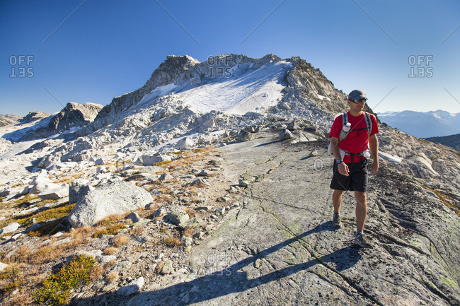 A backpacker hikes from Cassiope Peak towards Saxifrage Peak during a traverse trip
