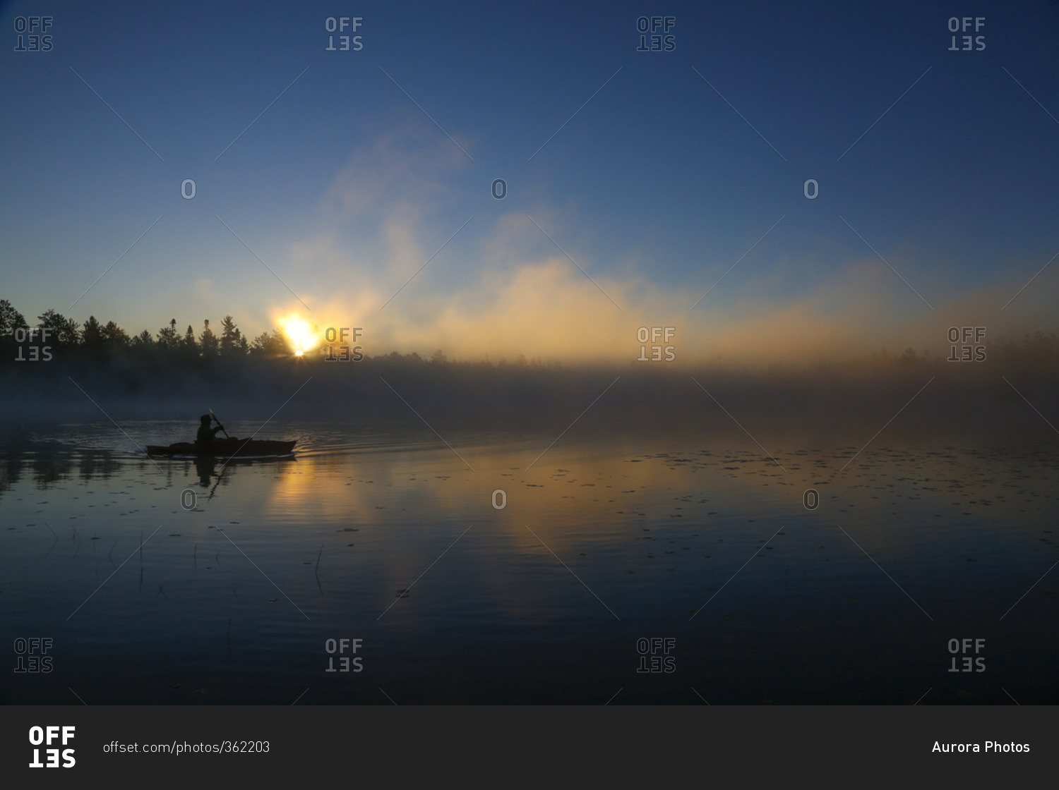 A kayaker enjoys the sunrise on a fog covered Lake Pleasant in Conover, Wisconsin on a brisk fall morning