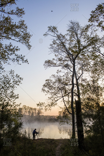 A silhouette of a man filming a documentary on the banks of the Chattahoochee River at dawn