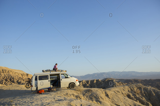 Borrego Springs, California, USA - January 1, 2000: Woman sitting atop a camper van taking in the view of the Badlands