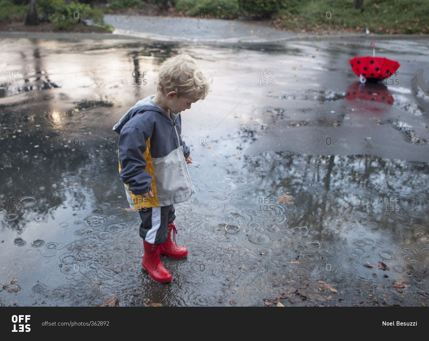 Boy in rubber boots plays in puddle