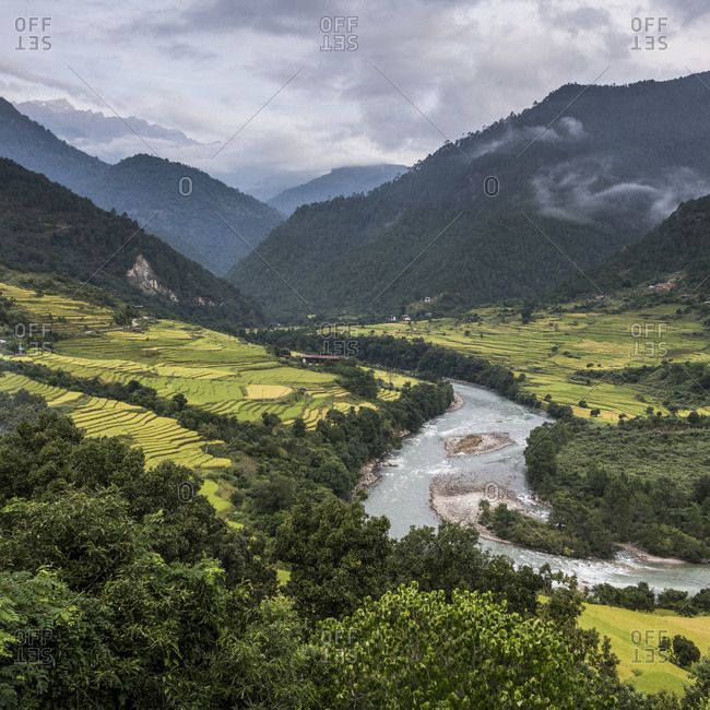 A river flowing through a valley with lush farmland surrounded by