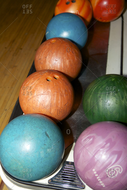 Many bowling balls lined up on a ball return
