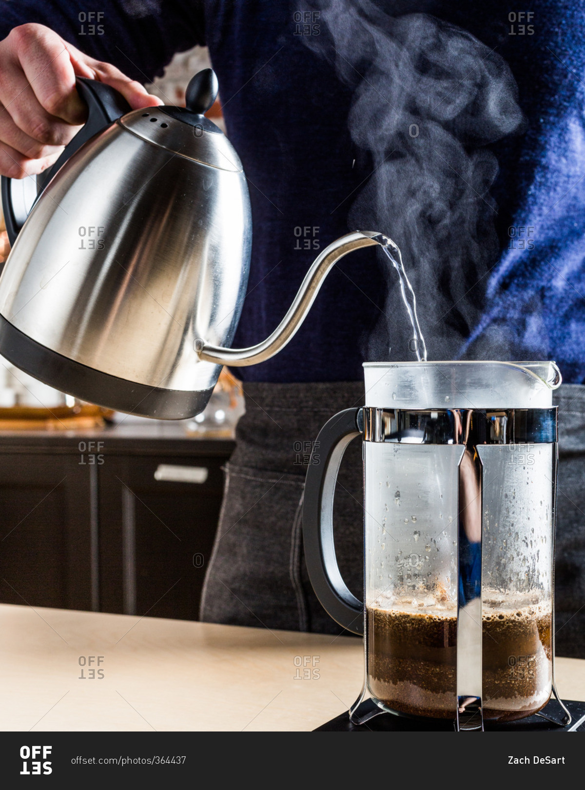 A person using a gooseneck kettle for a French press coffee