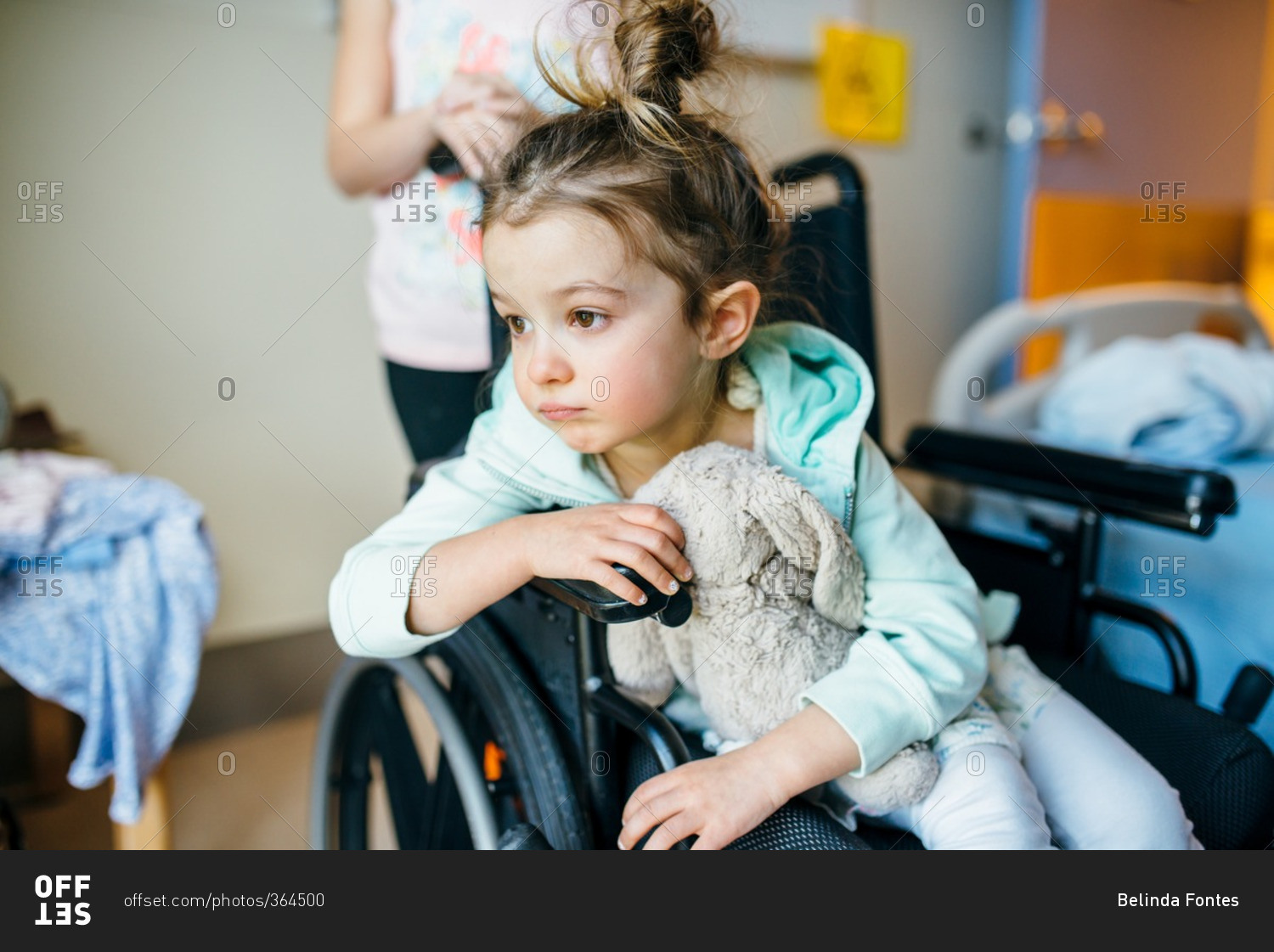 Little girl sitting in a wheelchair in a hospital stock photo OFFSET