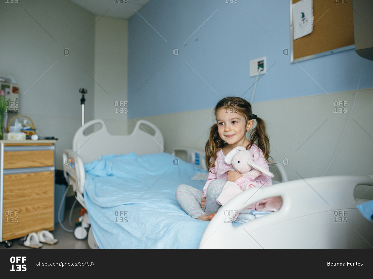Little girl sitting in a hospital bed stock photo OFFSET