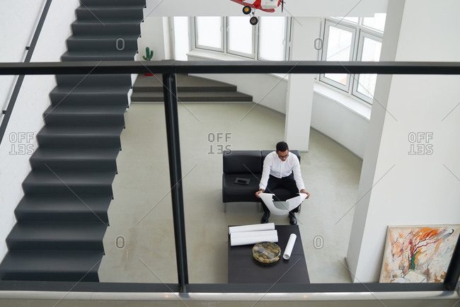 High angle view of man looking at blueprints