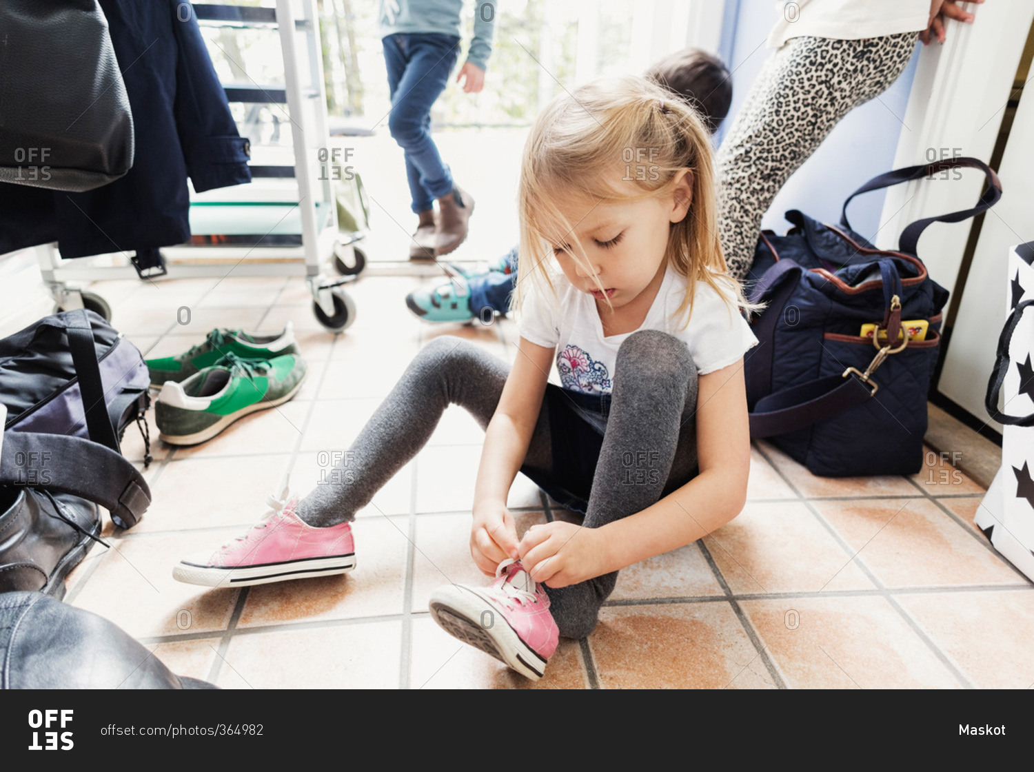 Girl wearing shoe while sitting on floor at day care center