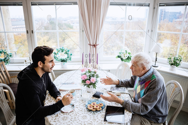 Senior man talking to caretaker at dining table in nursing home