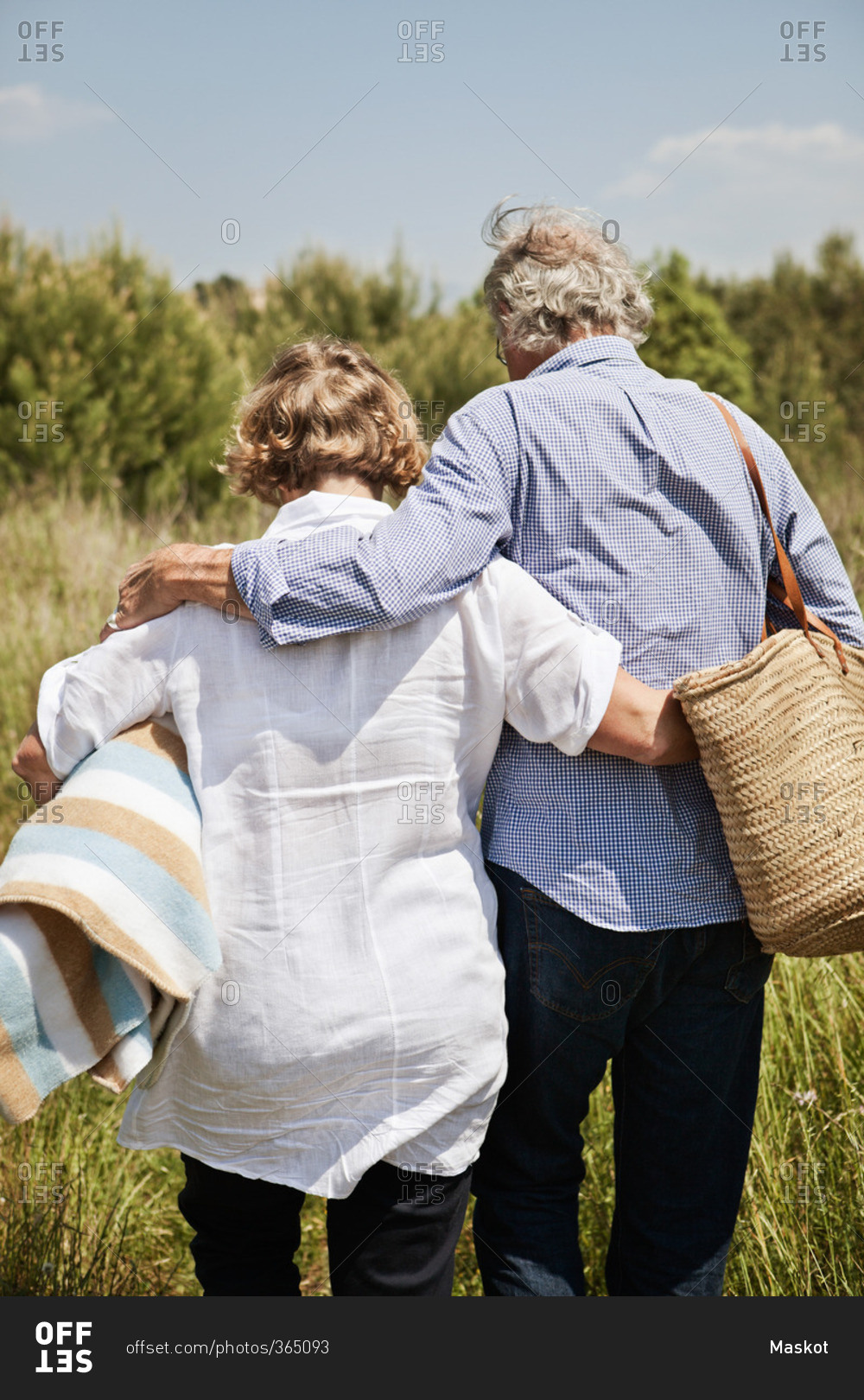 Couple with picnic basket and blanket going for picnic
