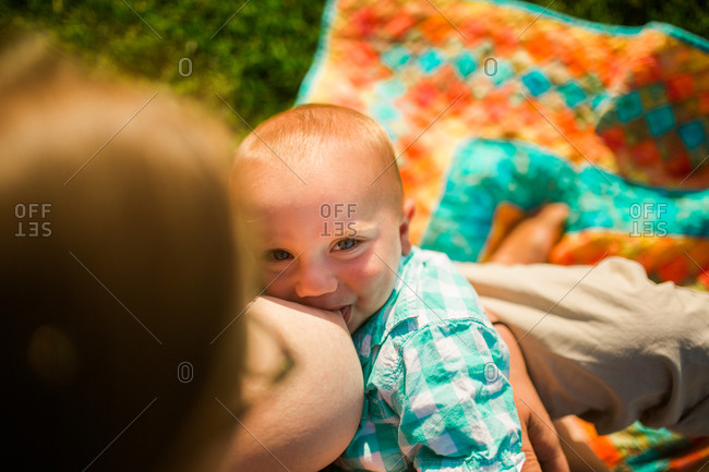 Mother breastfeeding her son outside on a blanket