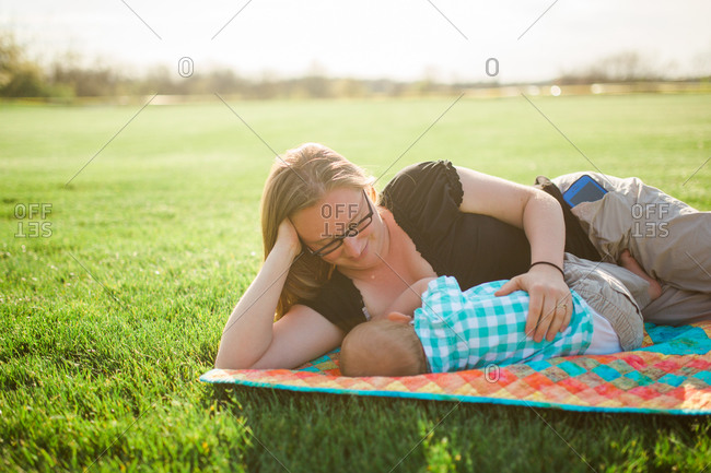 Mother breastfeeding her son outside on a blanket