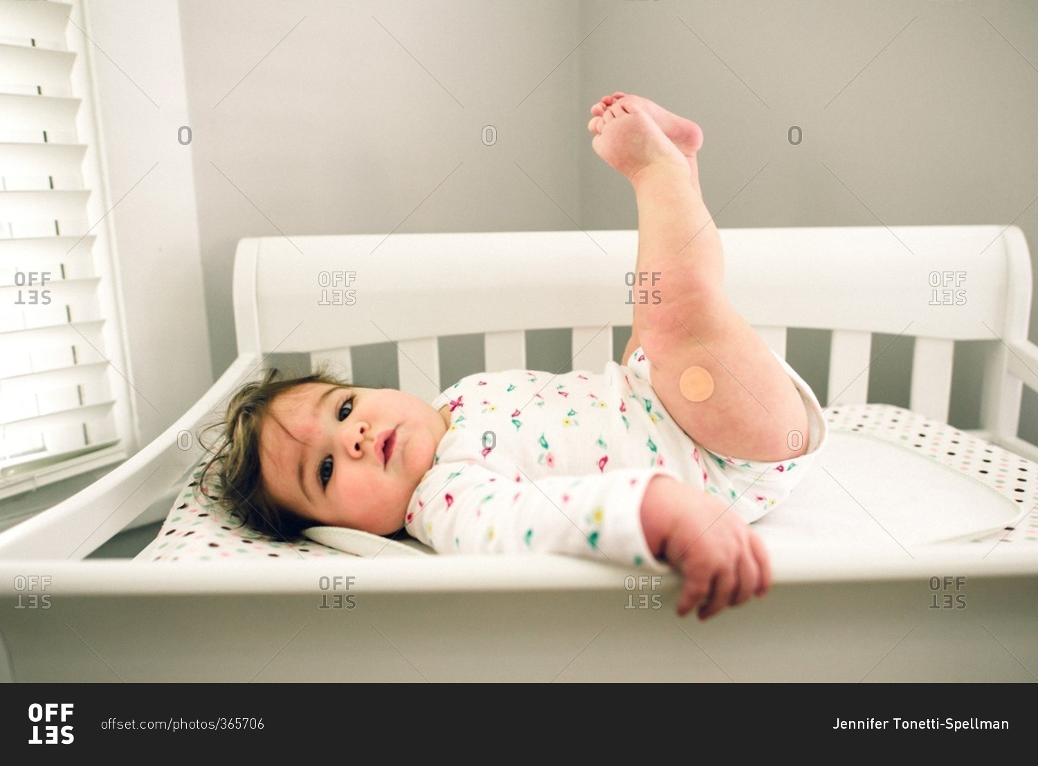 Baby girl lying down on changing table with legs raised stock photo