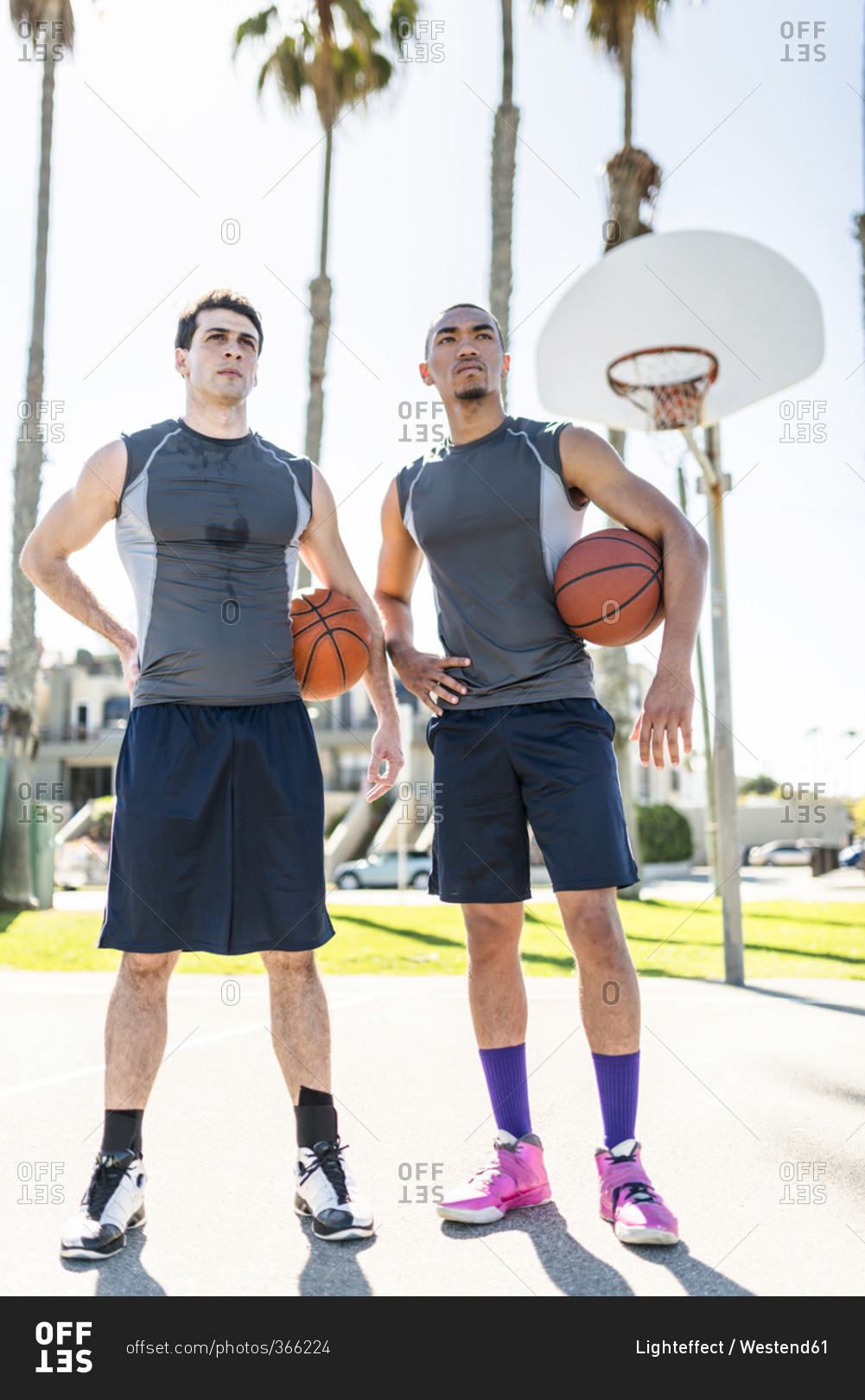 Two young men standing on outdoor basketball court