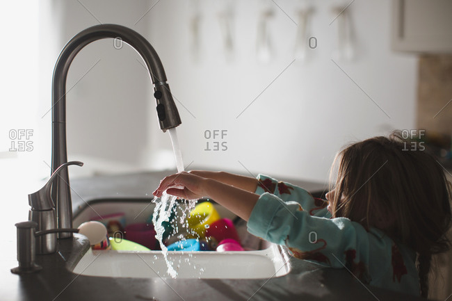 Girl rinsing hands at kitchen sink