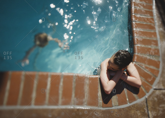 Boy resting at pool's edge