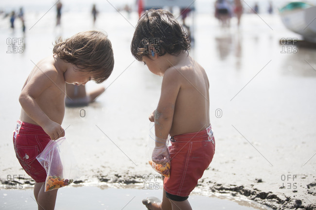 Twin boys playing in puddle on beach