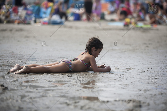 Young girl lounging on wet sand at beach
