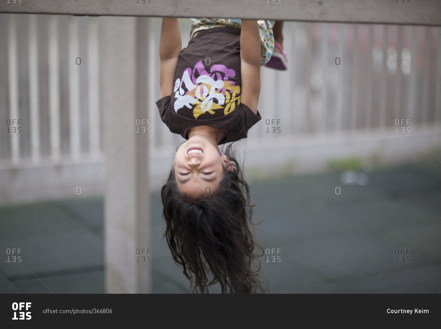 Portrait of young girl hanging upside down on monkey bars