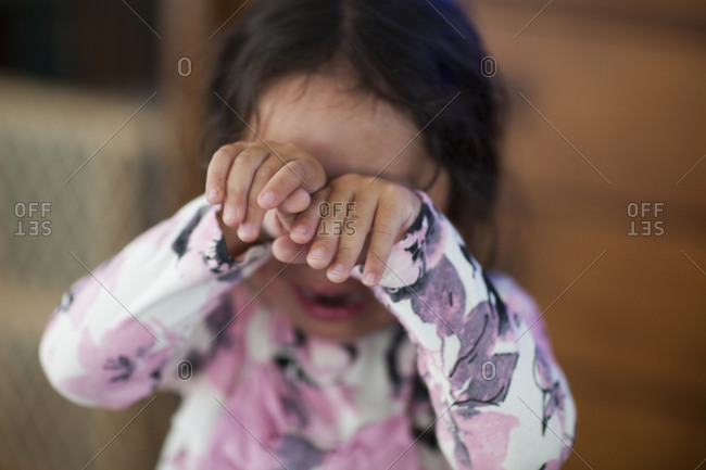 Crying young girl covering her eyes