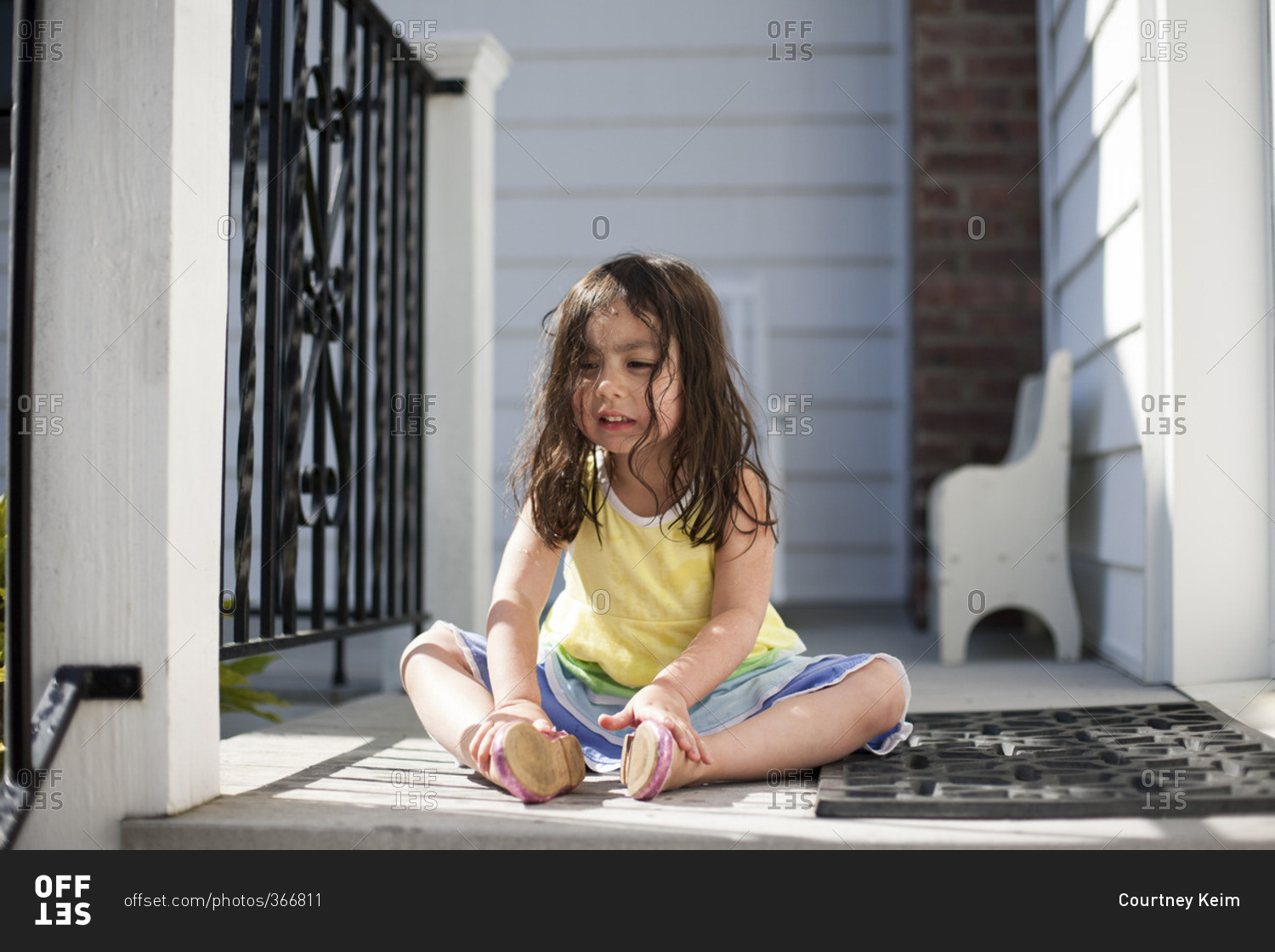 Sad toddler girl sitting on porch