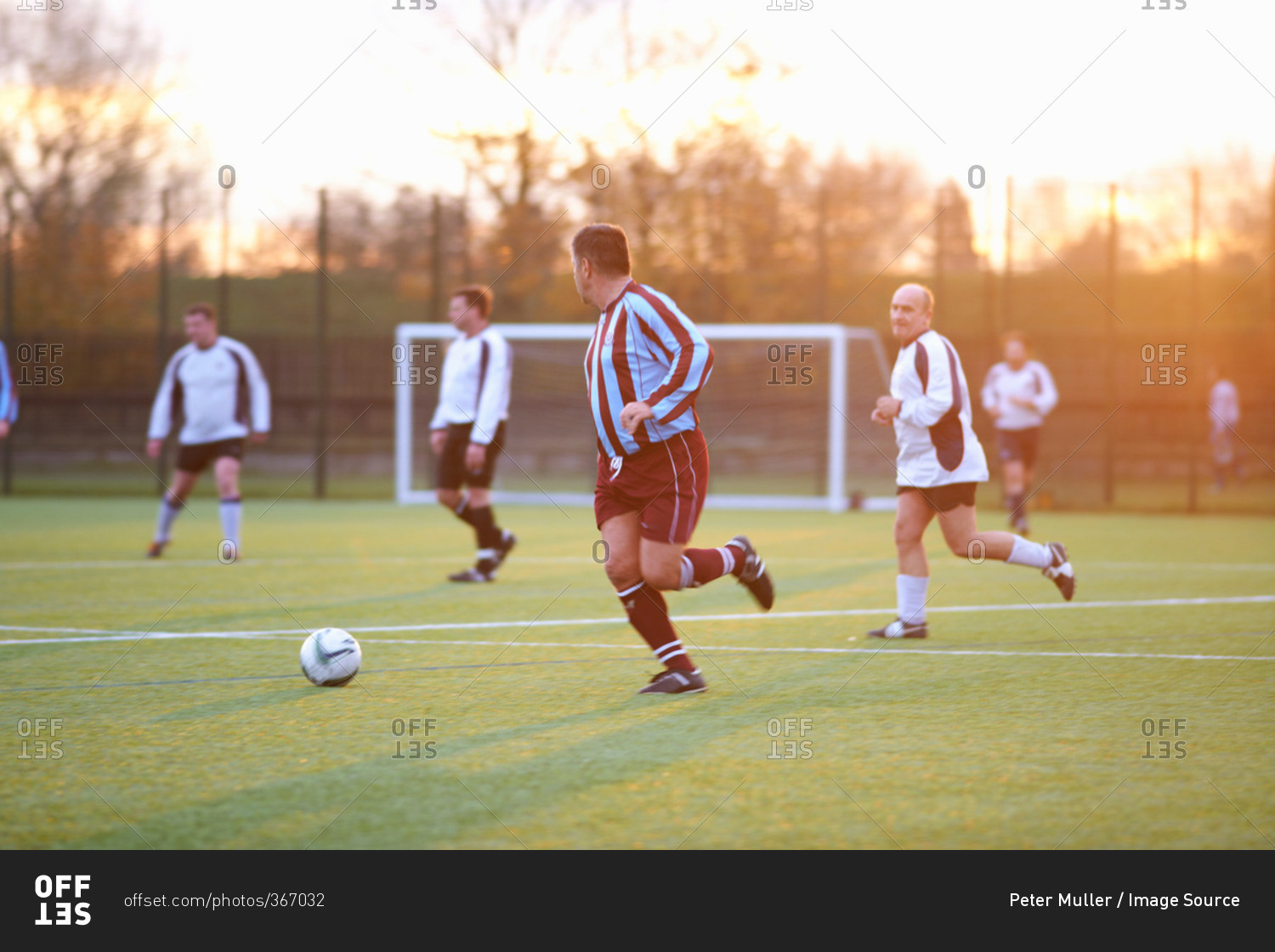 Soccer players running after ball