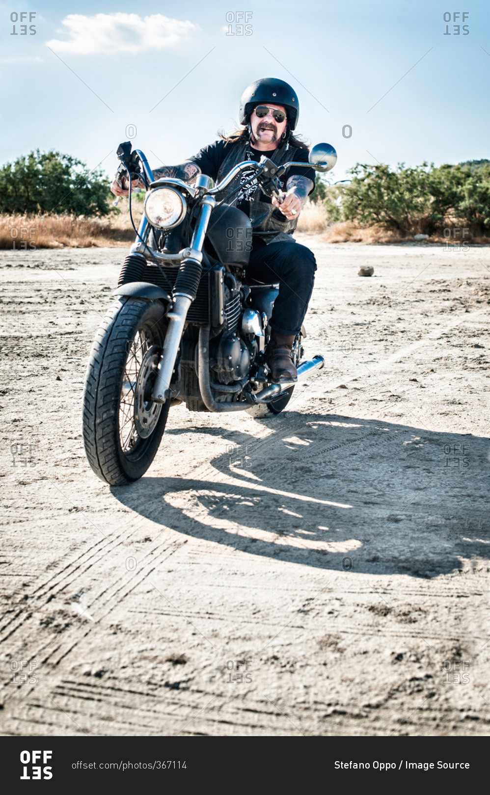 Mature man motorcycling across arid plain