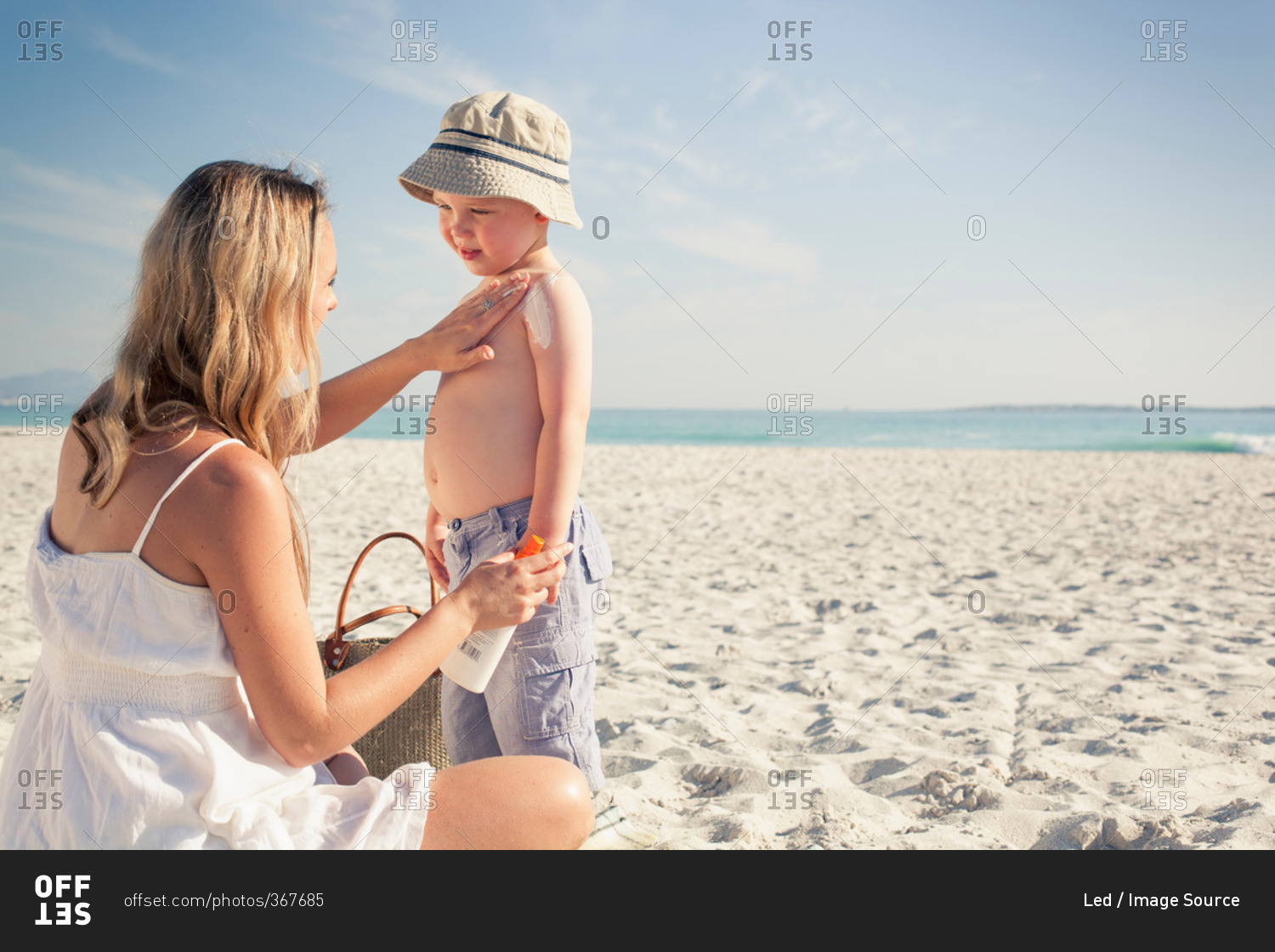 Mid adult mother applying sun lotion to young son on beach, Cape Town, Western Cape, South Africa
