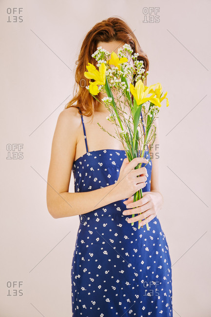 Woman covering her face with yellow and white flowers