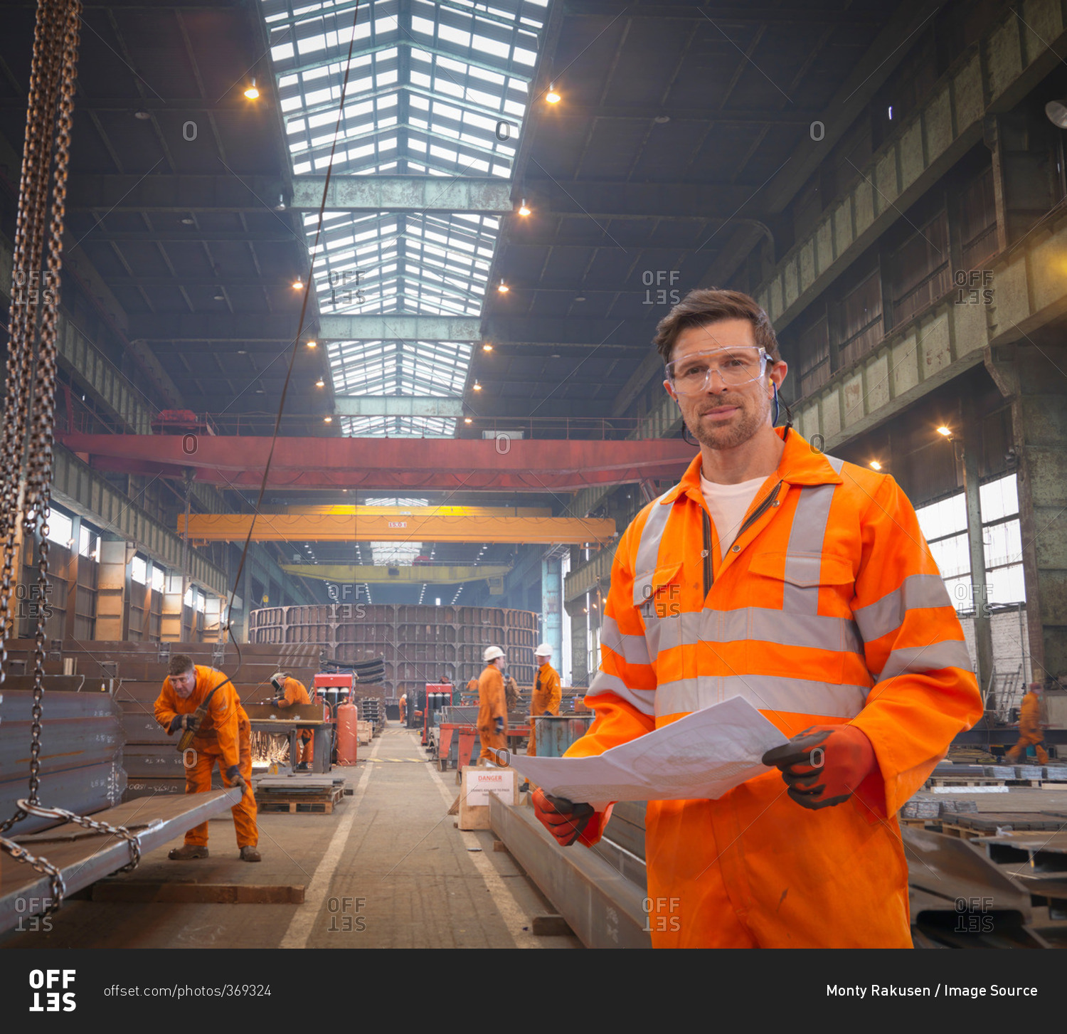 Engineer holding plans in marine fabrication factory, portrait