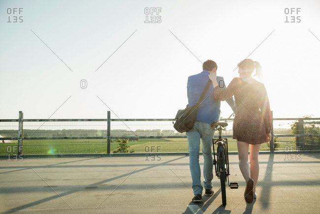 Young couple pushing bicycle in empty parking lot