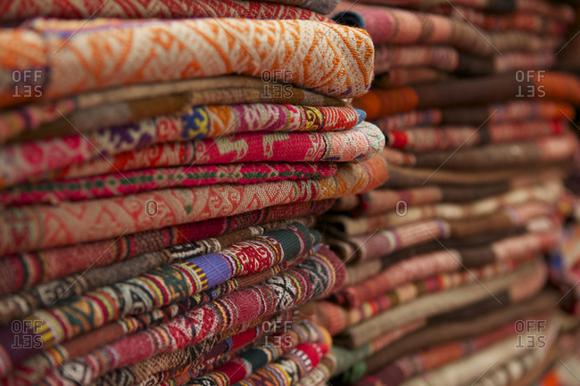 Stacks of folded woven textiles at Pisac Market, Cusco, Peru