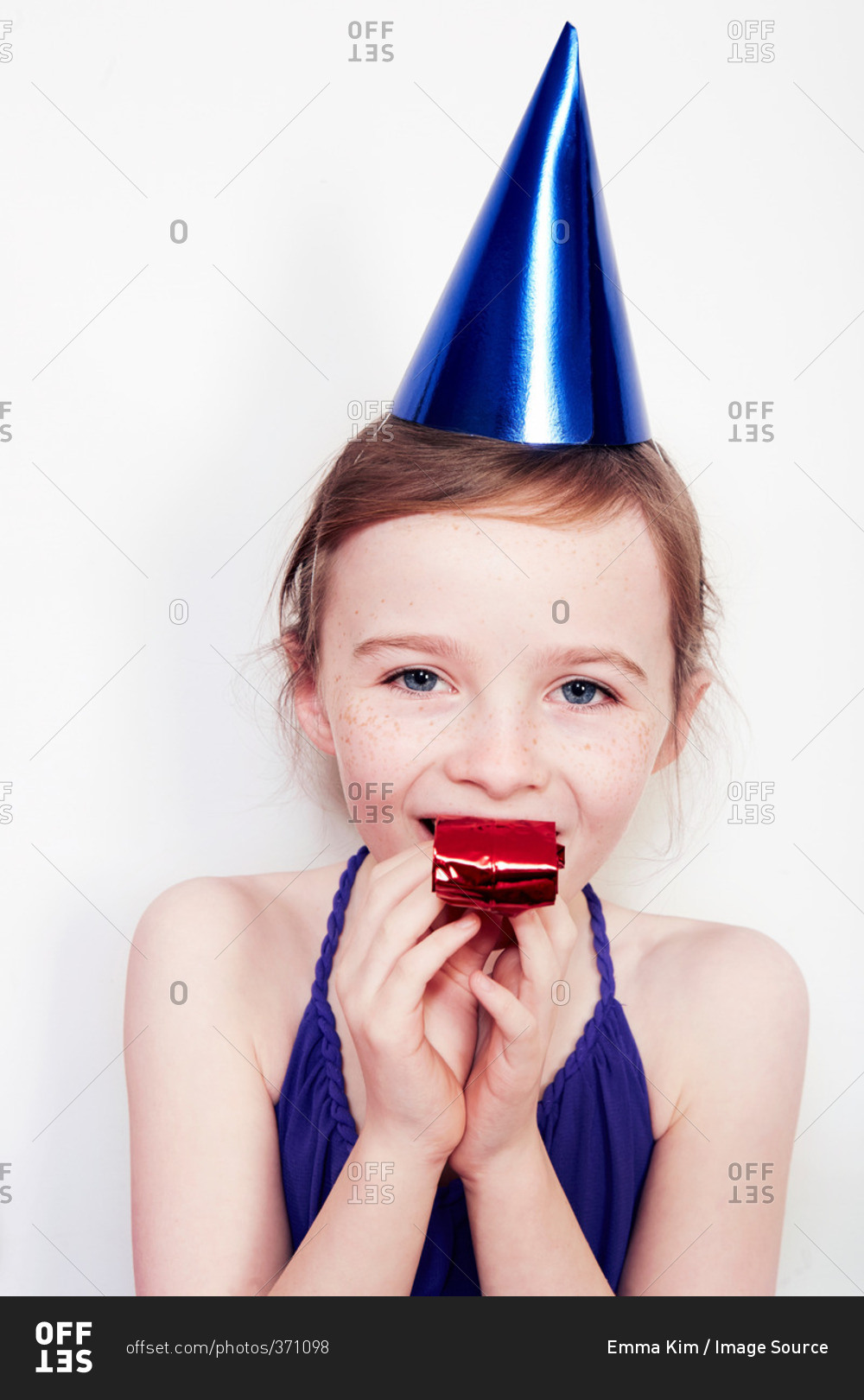 Portrait of girl with party blower wearing party hat