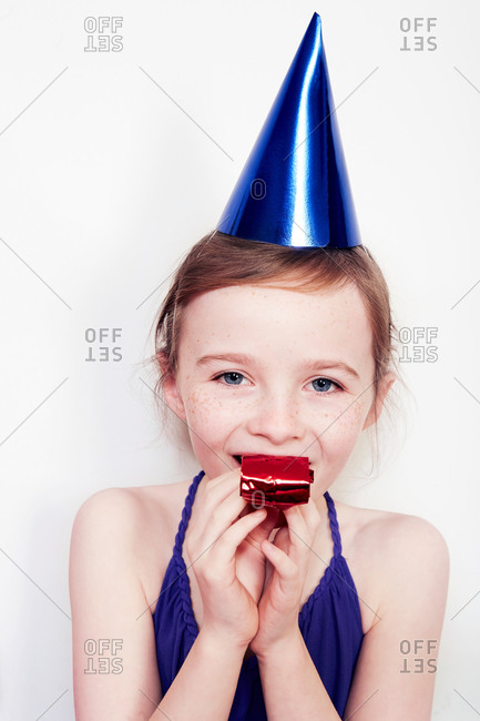 Portrait of girl with party blower wearing party hat