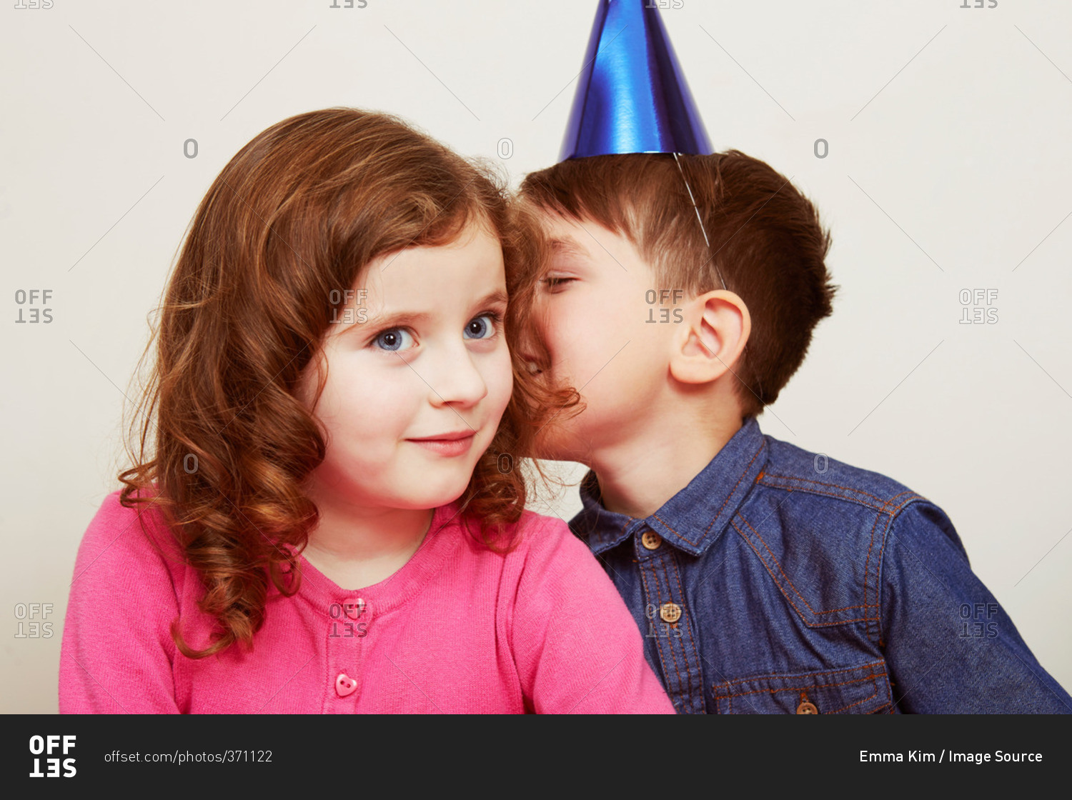 Boy wearing party hat whispering to girl