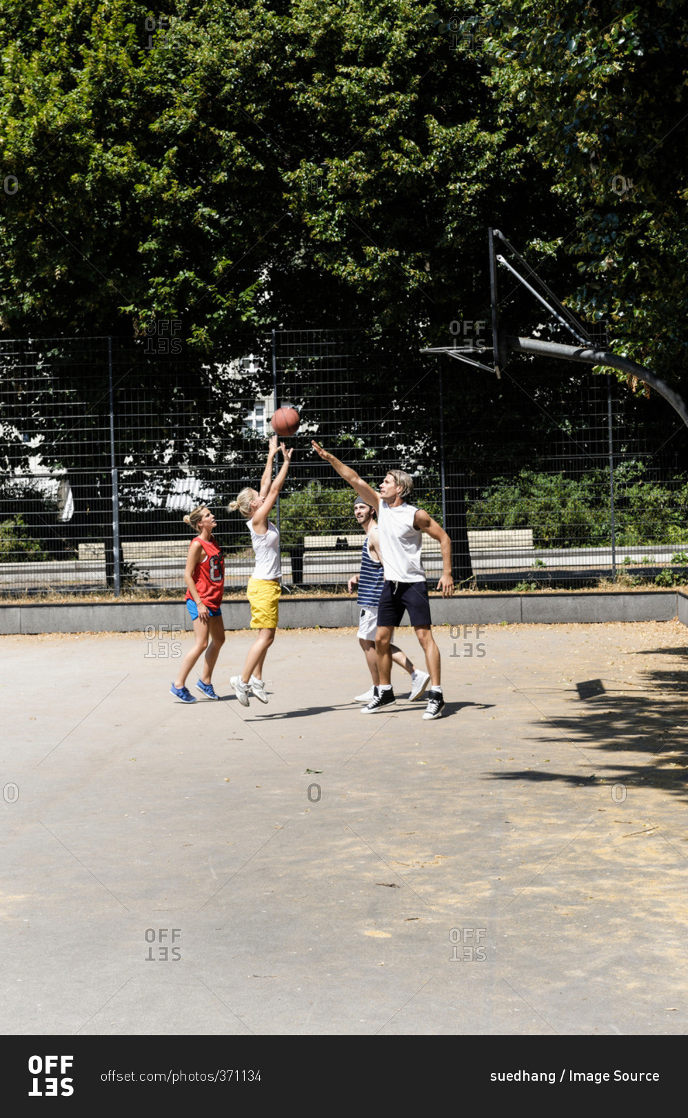 Group of friends playing basketball on court in park