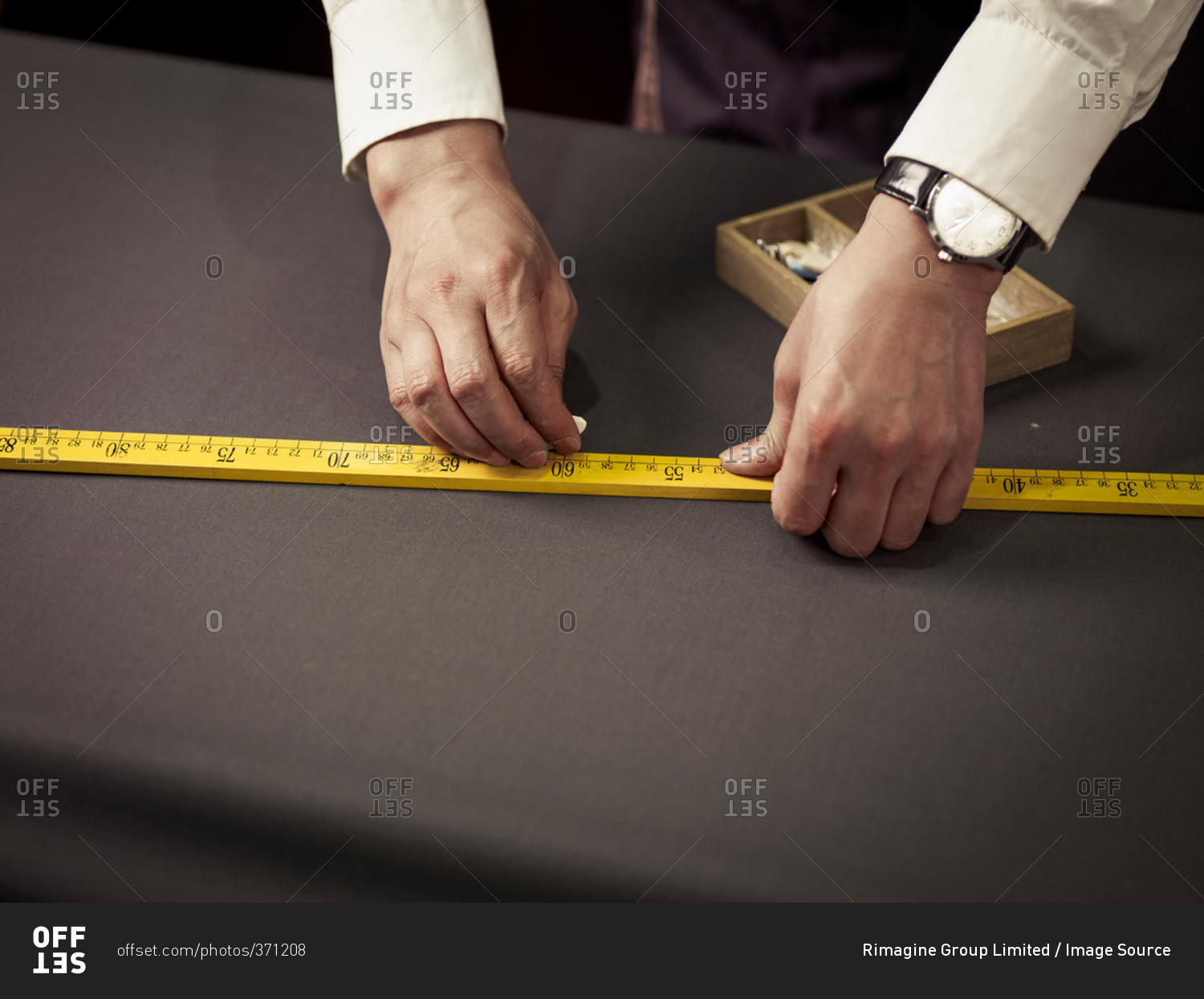 Tailor chalking measurements on table in traditional tailors shop