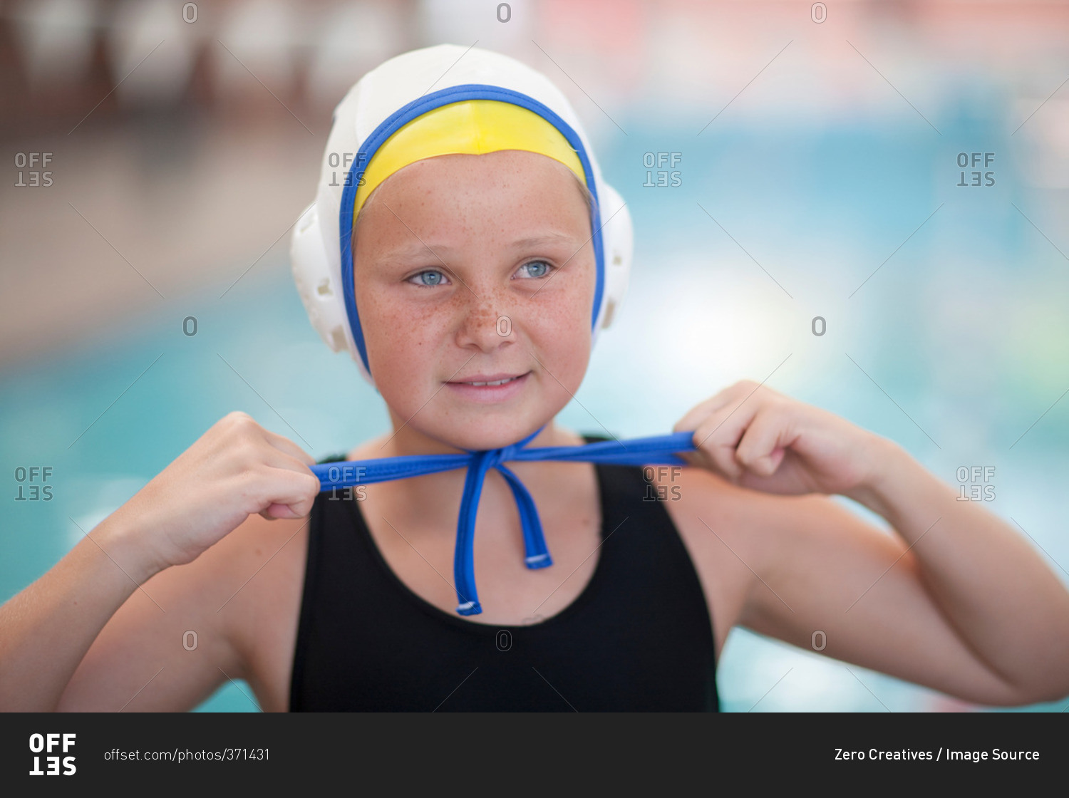 Portrait of school girl water polo player fastening swimming cap