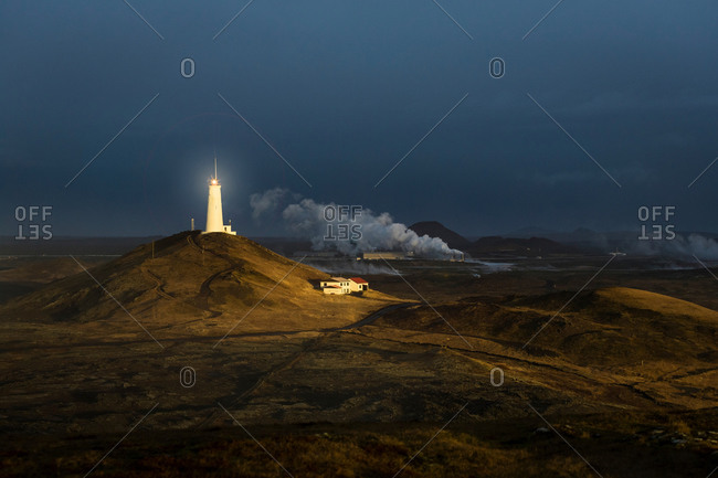 View of distant glowing lighthouse, Reykjanes, Iceland