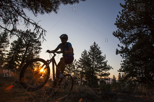 A woman mountain biker  is silohetted in the rising sun at Blue Mountain Recreation Area in Missoula, Montana