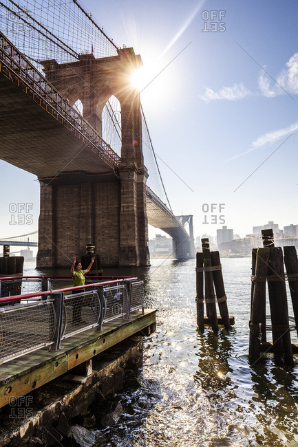 Woman practicing tai chi in the shadow of Brooklyn Bridge