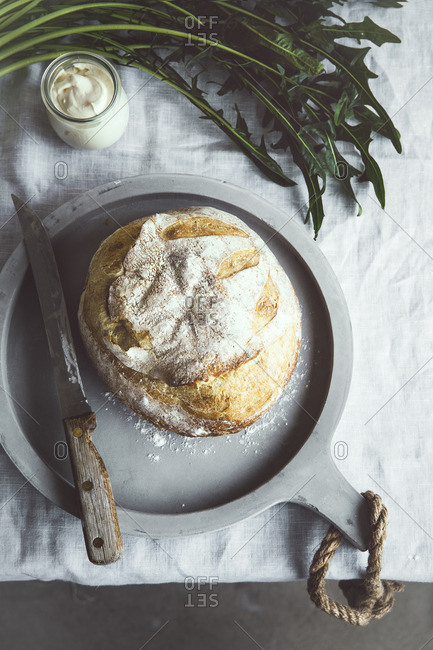 Fresh baked bread next to knife, jar of butter, and dandelion greens