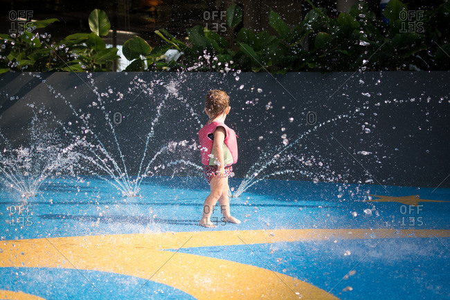 Little girl playing on a splash pad at a water park