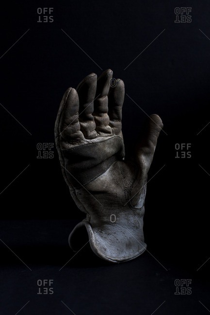 A used welder's glove on a black seamless background