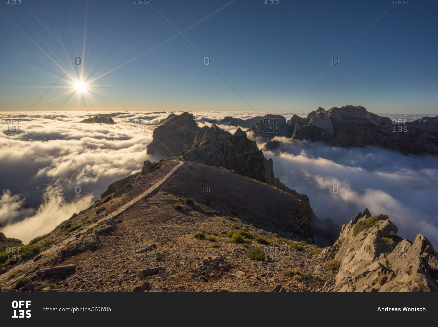 Sun shining above the clouds and peaks of the Pico do Arriero in Madeira, Portugal
