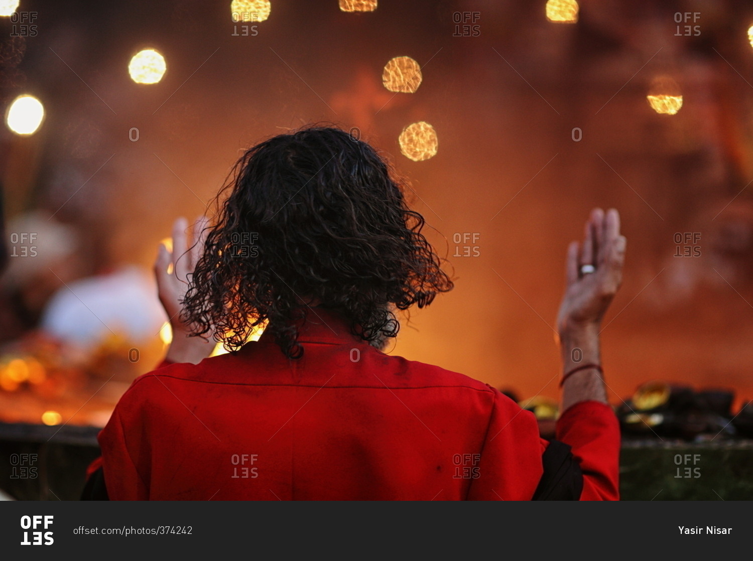 Man in a red jacket raising his hands in prayer