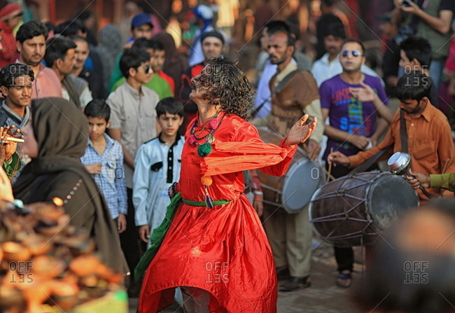 Pakistan - March 30, 2014: Man in colorful robes dancing to drum music in a square