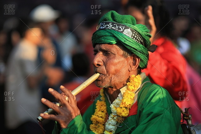 Pakistan - March 30, 2014: Senior man in traditional clothing playing a small pipe