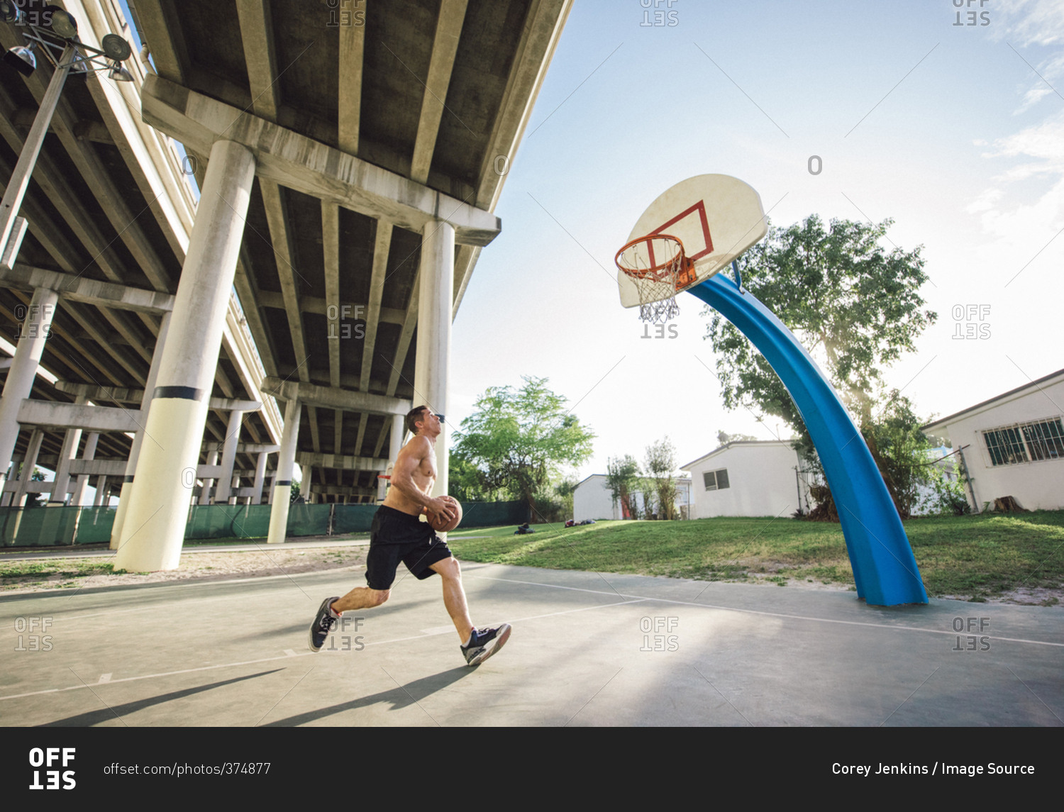 Side view of young man holding basketball running to basketball hoop